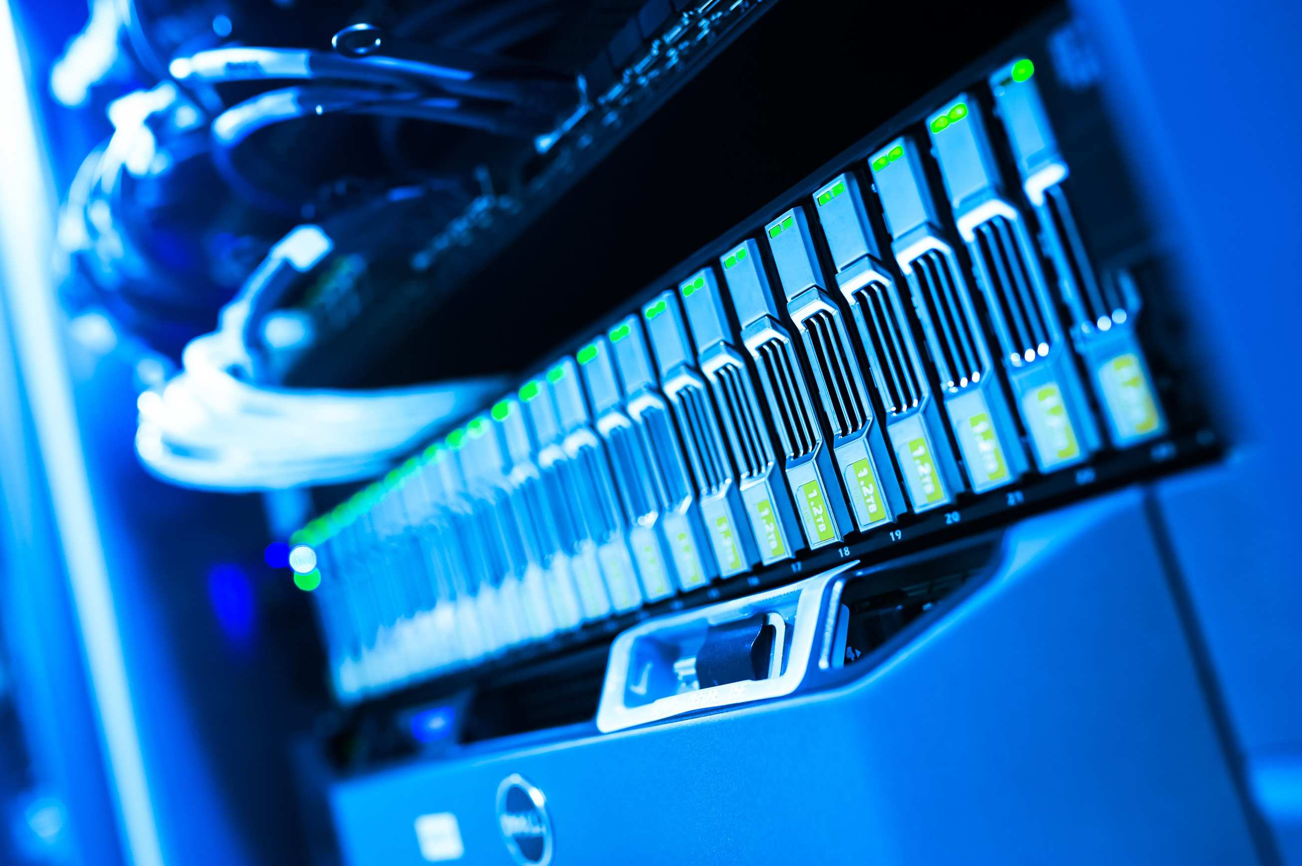 Server racks and network cabling in a data facility with a blue-lit computer server rack
